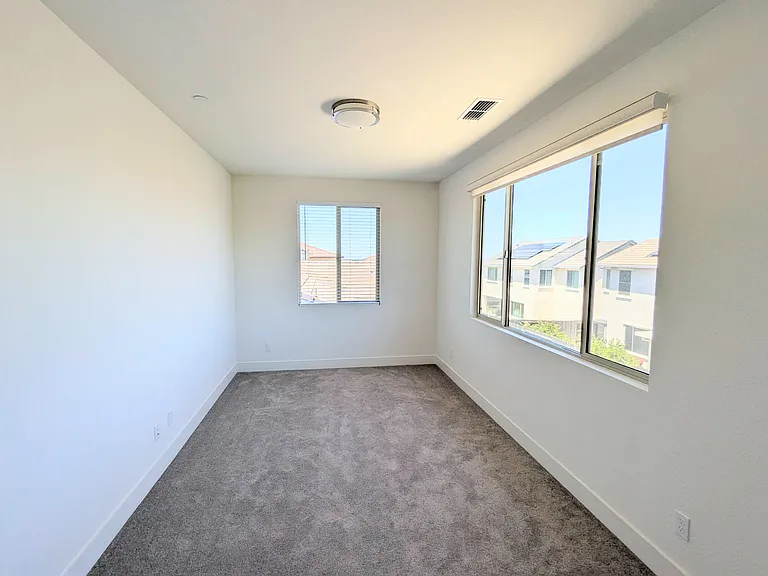 Enjoy floods of natural light in this spacious bedroom. Featuring expansive oversized windows equipped with elegant light filtering roller shades, this sun-filled retreat is a perfect private sanctuary.