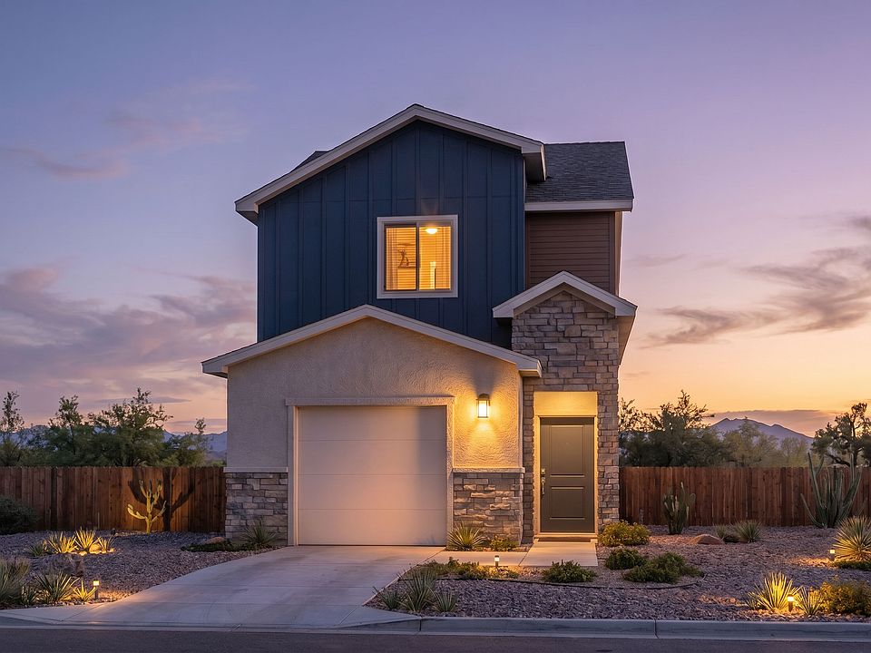 A modern two-story house with a mix of stone and siding exterior, a lit garage, and warm outdoor lig
