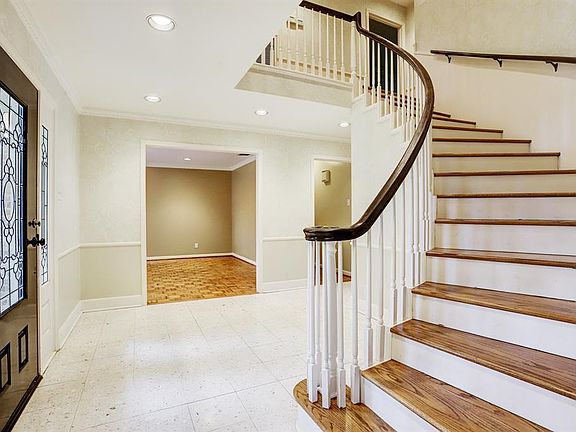 Visitors are greeted by a curved staircase as they enter the property.