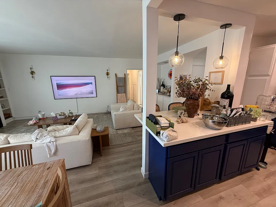kitchen with large island and bar counter for 3 stools adjacent to living room and dining area