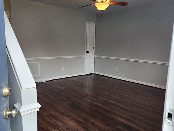 Spacious living room with hard wood flooring and ceiling fan