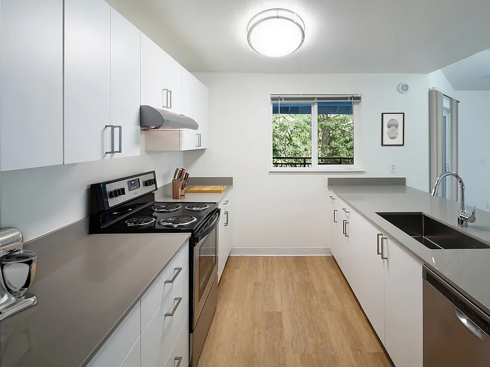 Renovated Package I kitchen with stainless steel appliances, white cabinetry, grey quartz countertops, and hard surface flooring