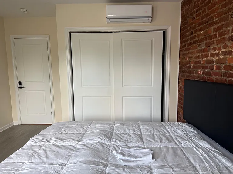 Private bedroom with a comfortable bed, sliding-door closet storage, and a wall-mounted mini-split for personalized comfort.