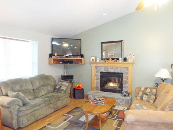 Inviting living room open to the dining area with vaulted ceilings and gas log fireplace. Hardwood flooring.