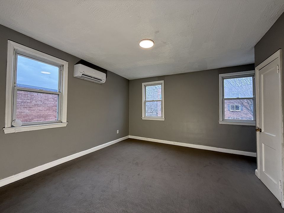 Spacious and bright with plush carpet, large windows, and a sleek wall-mounted AC unit.