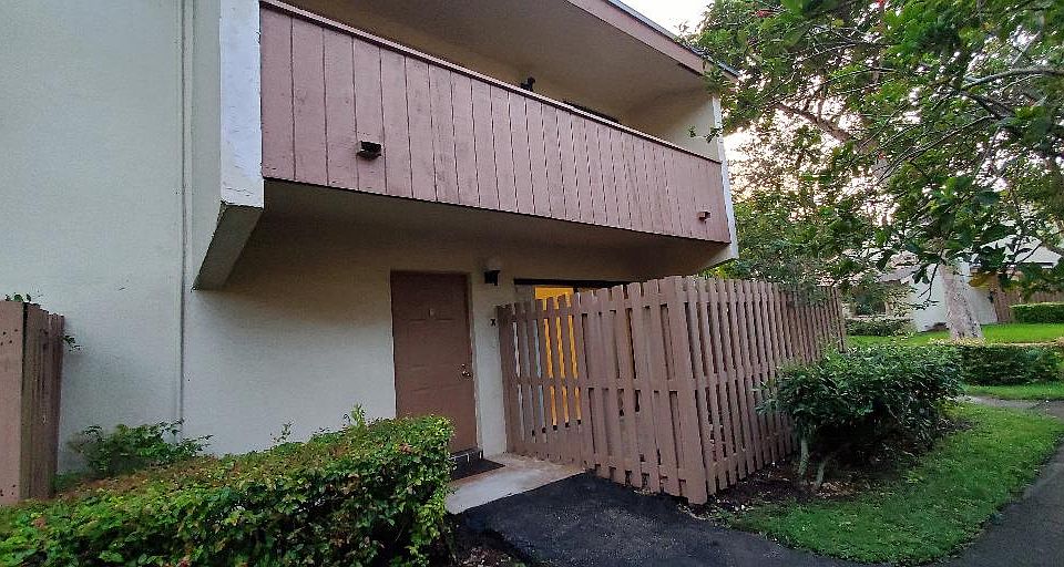 View of front door, private fenced patio and upstairs private master bedroom balcony.