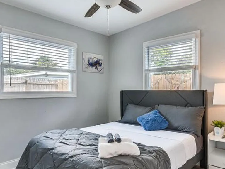 Well-appointed bedroom with two windows, a ceiling fan, and a nightstand for convenient bedside storage and lighting.