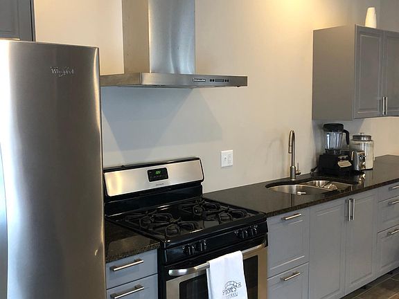 Renovated Kitchen: Stove hood with fan and lights, gas stove, stainless large refrigerator, and granite countertops