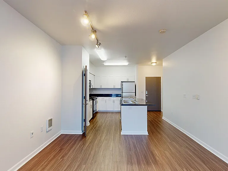Apartment kitchen, dining and living room with wood-style flooring.