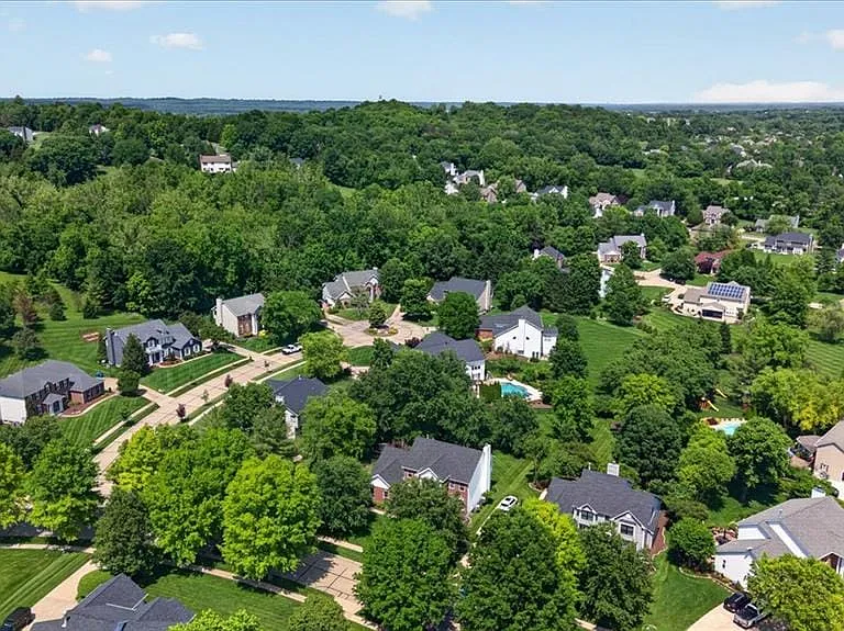 Expansive residential area featuring numerous properties set among abundant mature trees and verdant landscapes