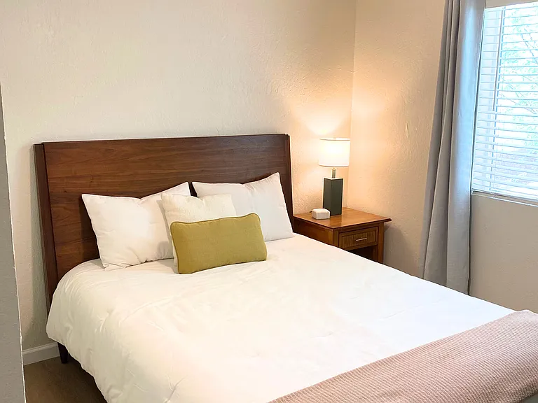 Bed 2 Queen size bed Bedroom 2 with a nightstand, lamp, blackout wood blinds, darkening curtains and a closet.