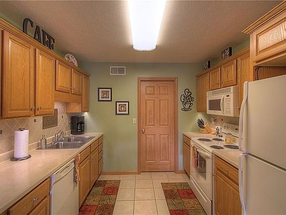 The kitchen offers an abundant amount of upper and lower cabinets, warmly elegant backsplash with copper inlays and features upg