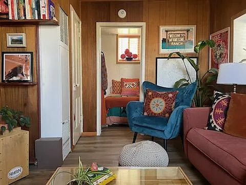 Living room. Main bedroom through doorway. Wall heater and closet to the left.