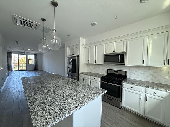 Full kitchen with island and storage. View into dining and living area.