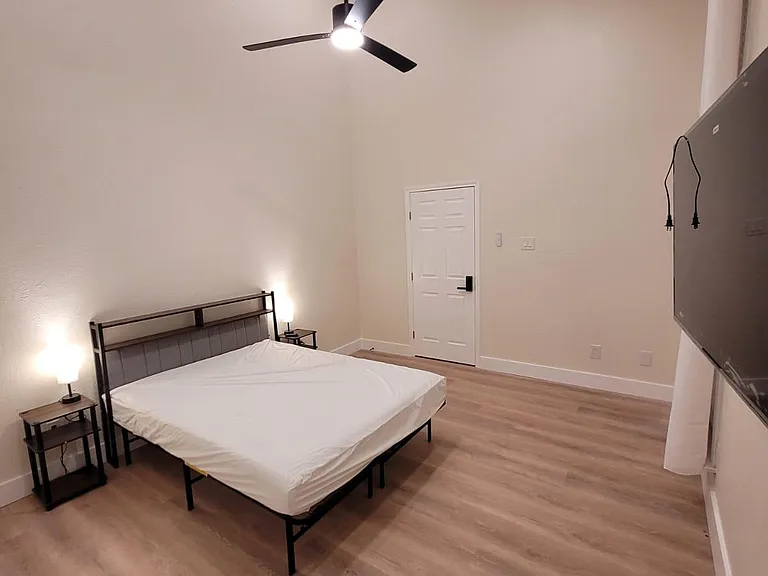 Spacious bedroom with high ceilings, ceiling fan, wood-look flooring, and room for a full setup plus storage.