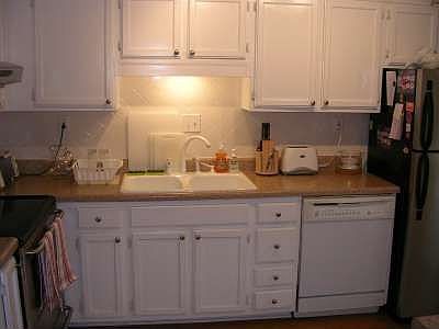 The well appointed kitchen features white cabinets, hardwoods & door to patiio