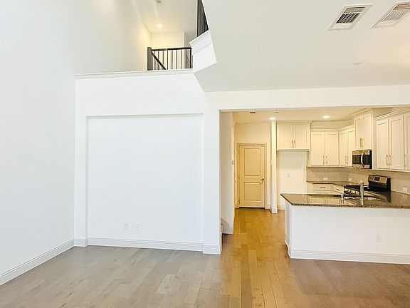 Living room with a 20-foot ceiling, ceiling fan, and wood-type flooring