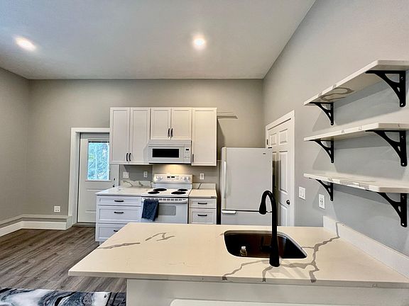 Small Kitchen but has quartz countertops and shelves, hardwood cabinets, and lots of drawers. Fridge with bottom freezer, over oven microwave with external ventilation fan