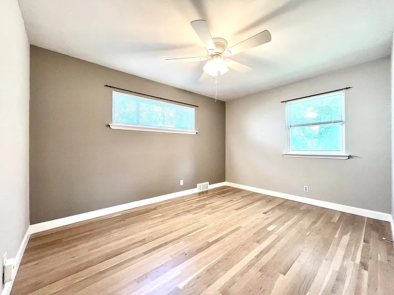 Primary bedroom with feature wall and overhead fan, overlooking back yard.