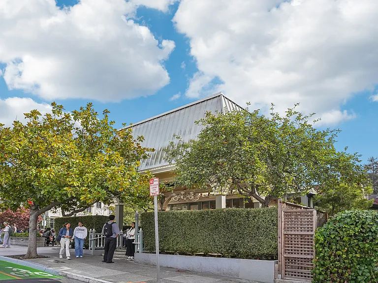 Group of people standing outside of a building with trees