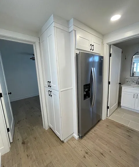 Stacked pantry cabinets adjacent to the full size stainless steel refrigerator