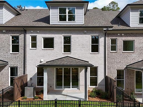 Rear view of property featuring a patio area, a fenced front yard, and brick siding