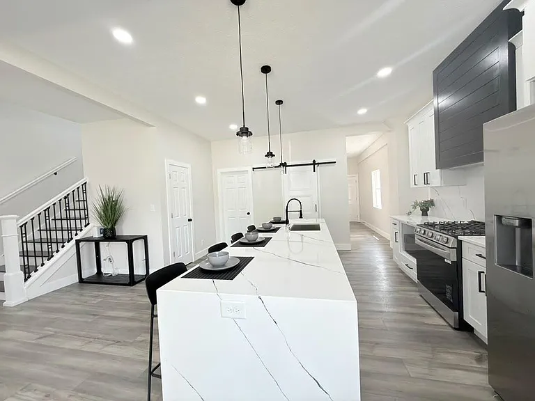 Open-concept kitchen with a large island, pendant lighting, and stainless steel appliances for easy meal prep and gathering.