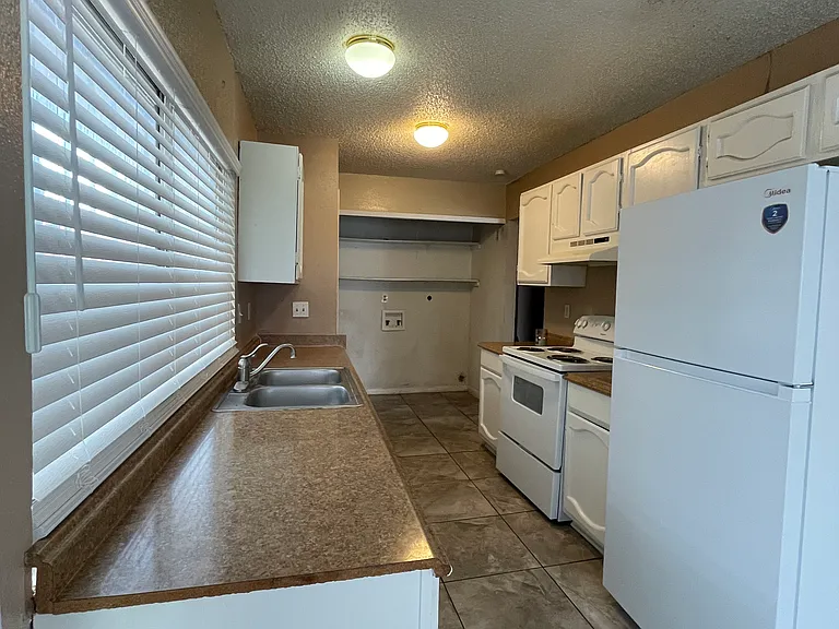 Kitchen with brand new stove, refrigerator and blinds.