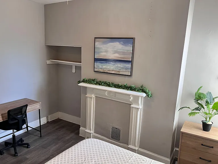 Bedroom features a decorative fireplace mantel, built-in shelving, and a dedicated desk nook for working or studying.