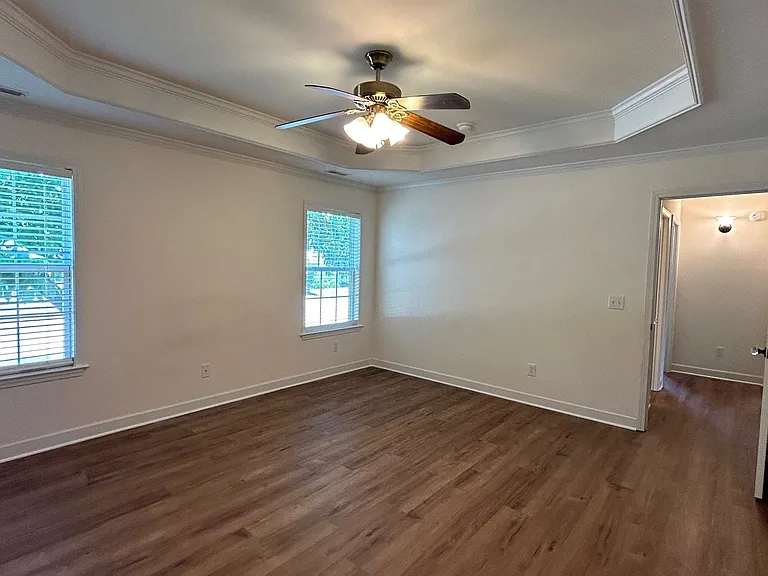 Master bedroom with ceiling fan, tray ceiling, and large walk-in closet
