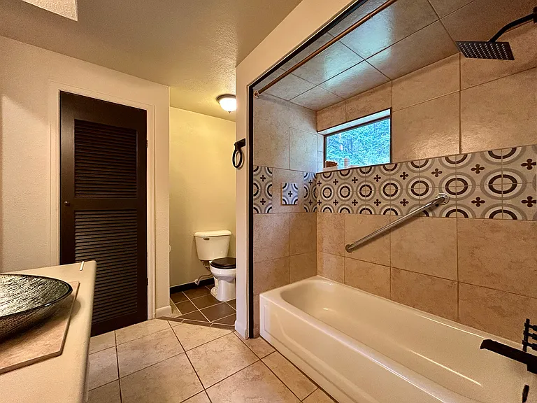 Retro backsplash and waterfall shower, safety rail, and elegant black tub fixtures