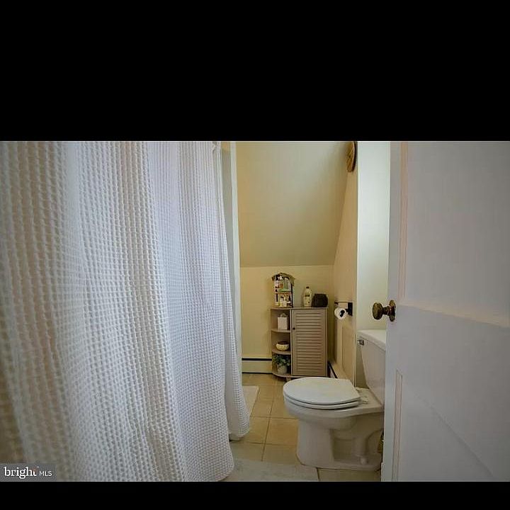 Bathroom with stand up tiled shower and vanity with storage.