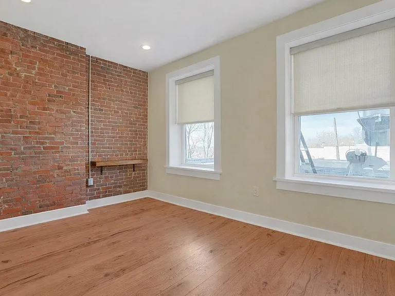 Bedroom: Light-filled bedroom with exposed brick walls and built in shelving.