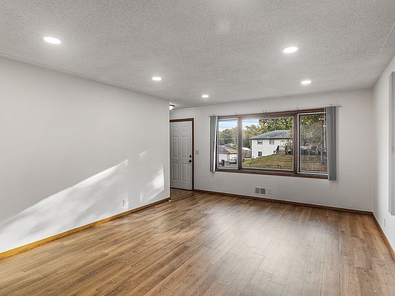 Main Level Living Room: Bright and spacious living room with large windows, dimmable recessed lighting, and beautiful LVP flooring, perfect for quality family time or hosting fun gatherings.