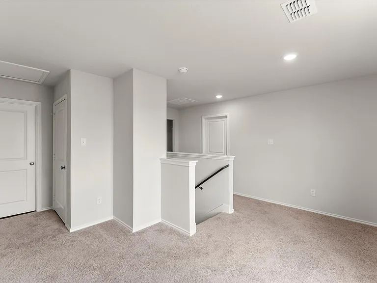Carpeted upper level featuring a white baluster and railing, flush-mount lighting, and light-toned wall finishes