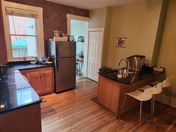 Stainless steal appliances (oven, refrigerator, dishwasher), exposed brick, and conversational island and bar seating in the kitchen.