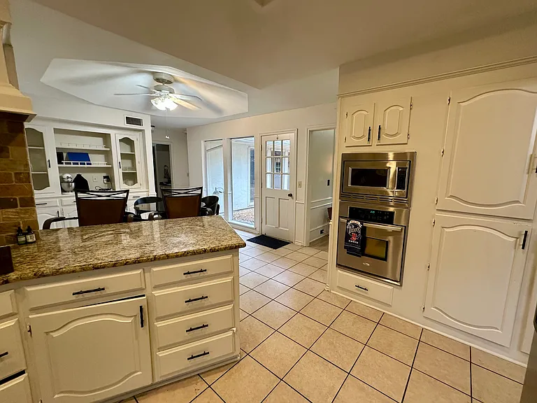 Kitchen with white cabinets, ceiling fan, stainless steel appliances, light tile patterned floors