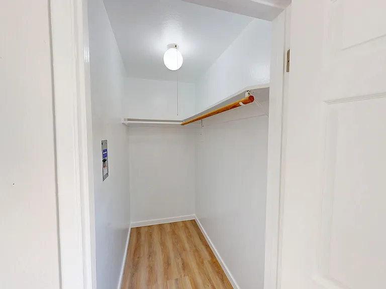 Bright and spacious walk-in closet featuring elegant wooden flooring and modern lighting. Bright and spacious walk-in closet featuring elegant wooden flooring and modern lighting.