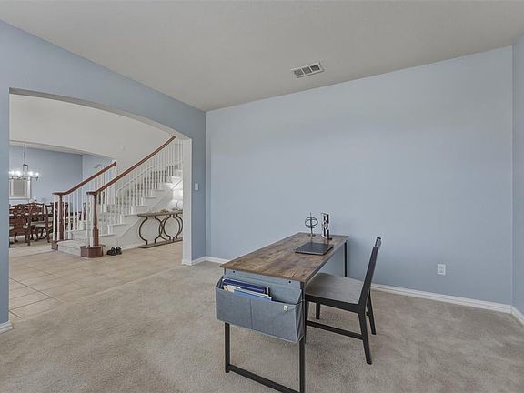Home office OR Formal Living room featuring light colored carpet, arched walkways, and hanging lights