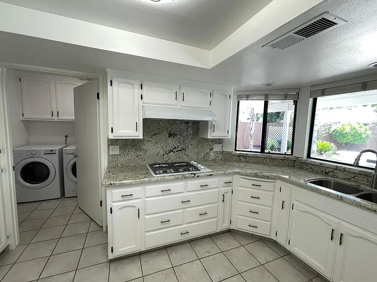 Washer and dryer right next to the kitchen in a separate room that includes a large sink and additional batroom