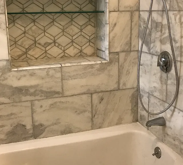 ceramic tile bath with shelving, overhead shower and hand spray.