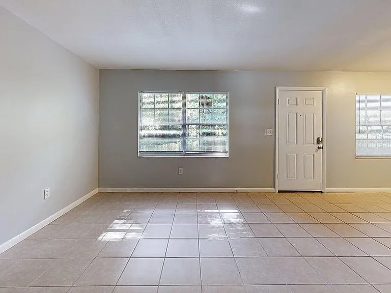 Bright and spacious living area with tiled flooring and large windows, perfect for modern living.