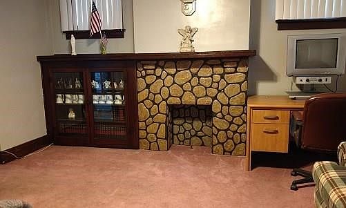 The glass door built-in bookcase beside the deco stone fireplace (with it's natural wood mantle) add "charm" to the formal Livin
