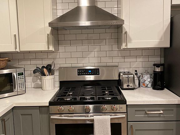 Gas stove oven with exhaust vent and fully stocked kitchen.
