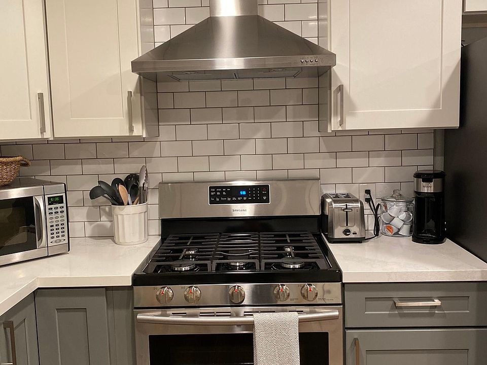Gas stove oven with exhaust vent and fully stocked kitchen.