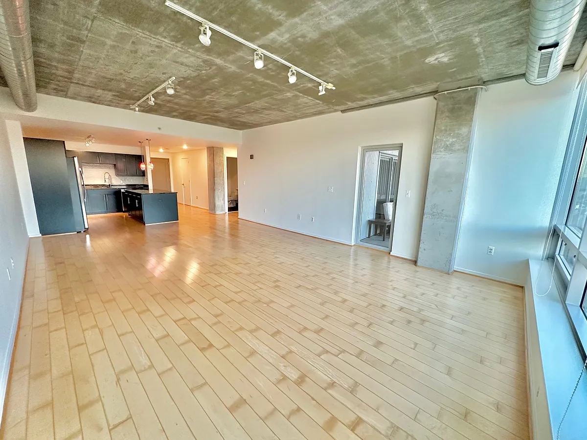 Main living and dining area with exposed concrete columns and ceiling. The entire unit was freshly painted Cloud White with Benjamin Moore Aura. Easy access to the private balcony. - 1200 Steuart St #320