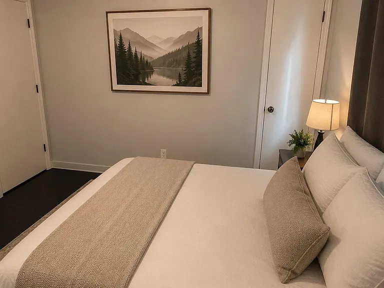Private bedroom with a full-size bed, nightstand lighting, and a calming wall art accent for a restful setup.