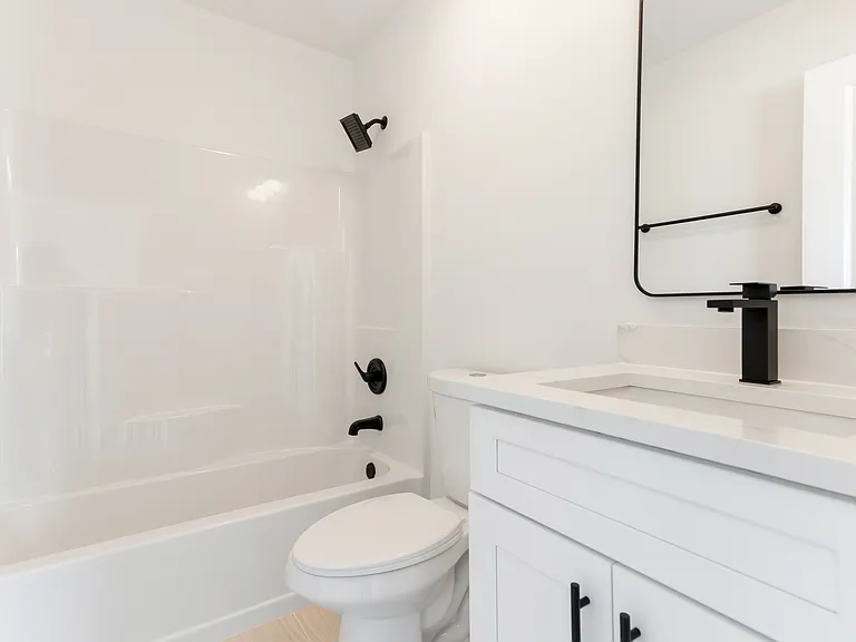 Bedroom one bathroom with tub. The shower rod is also black and curves out. It has the shower double curtain hooks that match for a liner and outer curtain.