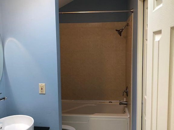 Ensuite master bathroom with tile floor and bathtub, double vanity and skylight