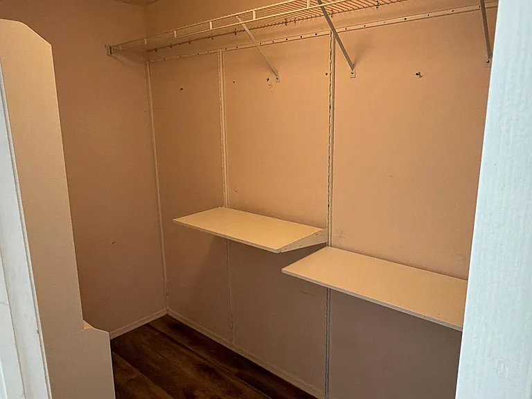 Walk in closet is equipped with custom shelving.